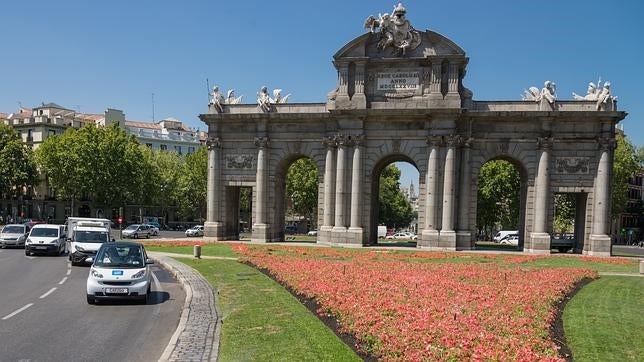 Uno de los vehículos compartidos pasa por delante de la Puerta de Alcalá